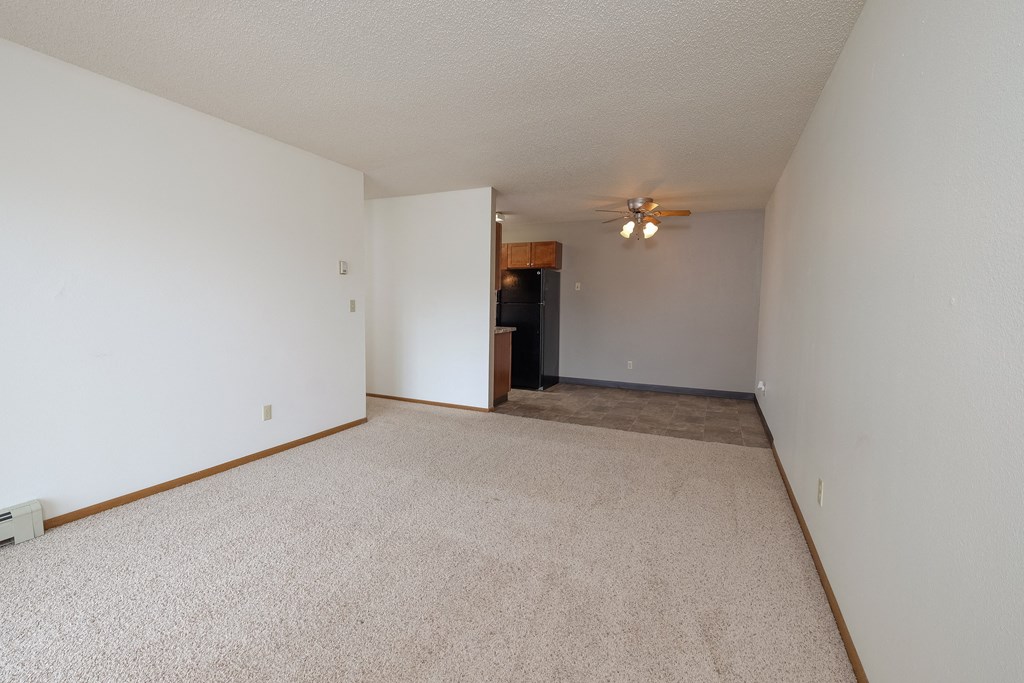 a spacious living room with carpet and a ceiling fan. Fargo, ND Carlton Place Apartments