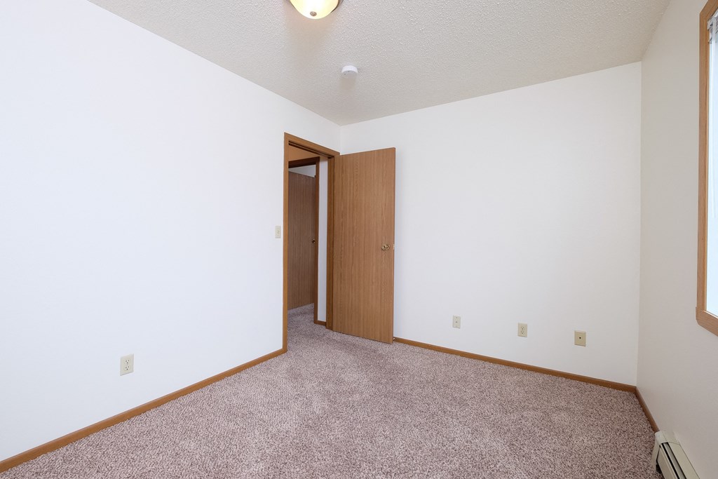 a bedroom with carpet and a door to a closet. Fargo, ND Carlton Place Apartments