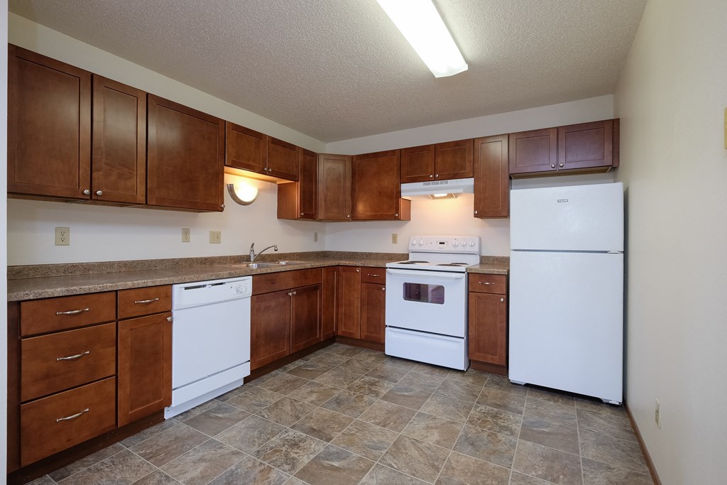 an empty kitchen with white appliances and wooden cabinets