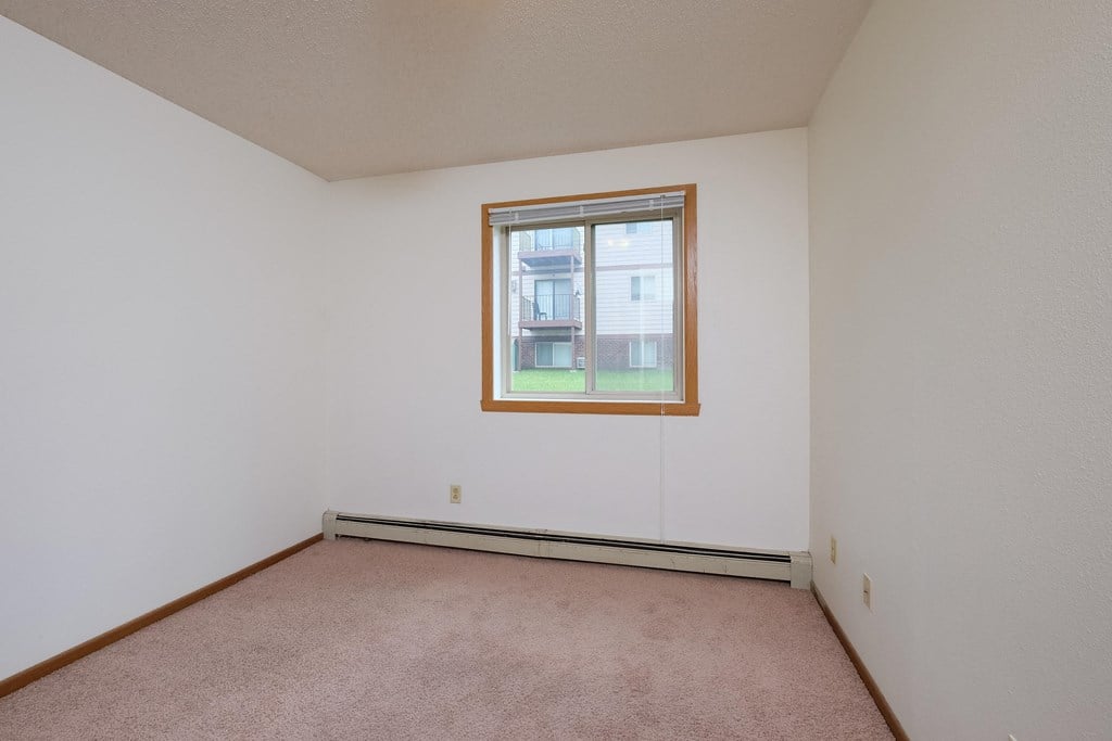 a bedroom with white walls and a window. Fargo, ND Carlton Place Apartments