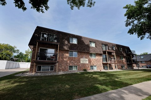 a brick apartment building with a lawn and a blue sky