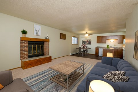 Fargo, ND Cedars 2 Apartments a living room with a blue couch and a wooden coffee table in front of a fireplace