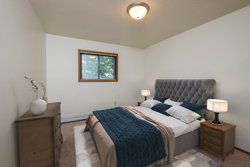 a bedroom with a large bed and a window. Fargo, ND Cedars 2 Apartments