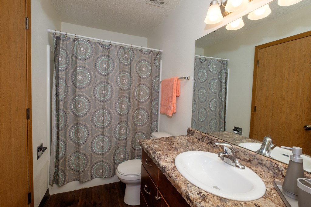 a bathroom with a sink and a shower and a toilet. Fargo, ND Cedars 2 Apartments