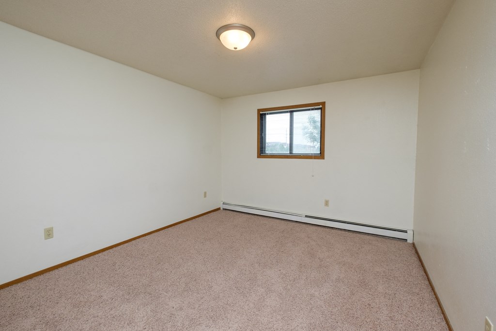 a bedroom with white walls and a window. Fargo, ND Cedars 2 Apartments