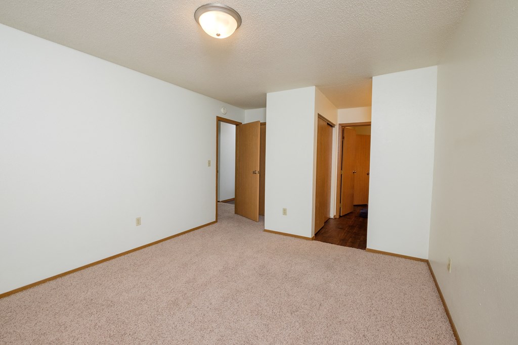 an empty bedroom with white walls and a beige carpet. Fargo, ND Cedars 2 Apartments