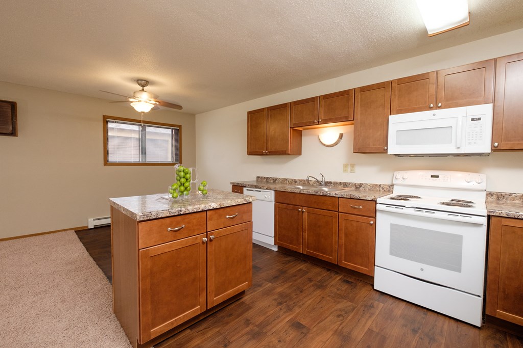 a kitchen with white appliances and wooden cabinets. Fargo, ND Cedars 2 Apartments