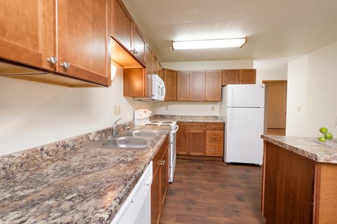 a kitchen with marble counter tops and wooden cabinets and a white refrigerator