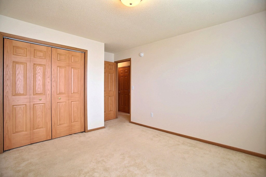 An empty room with wooden doors and a white wall