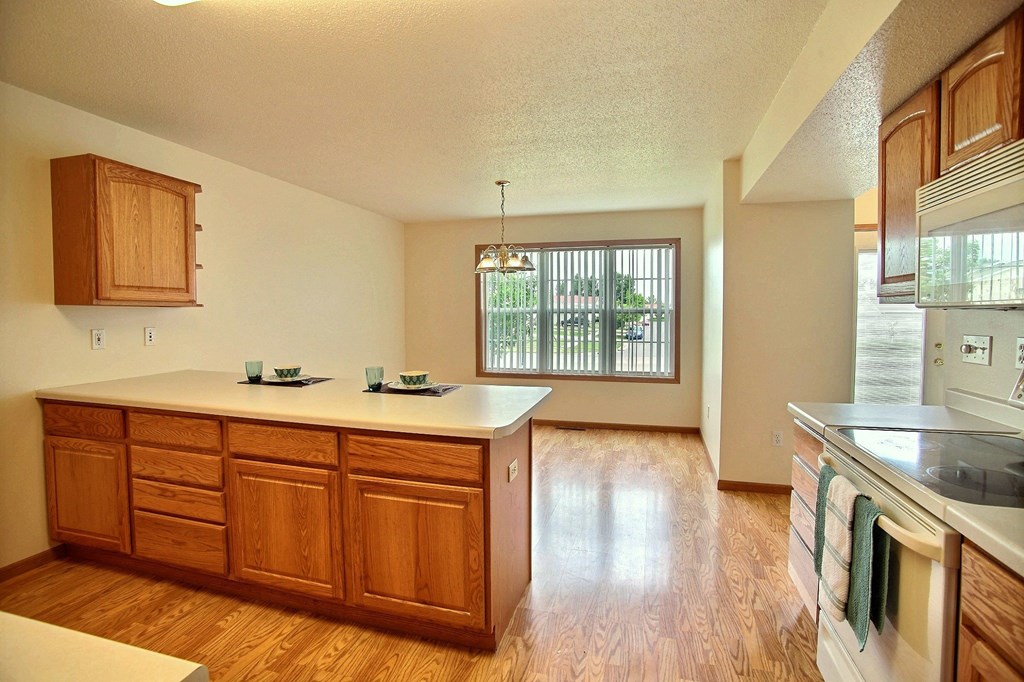 An empty kitchen with wooden cabinets and a white counter top
