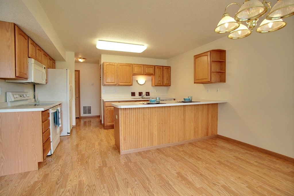 A kitchen with wood flooring and wooden cabinets and a counter top