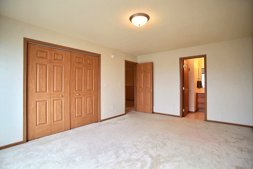 A bedroom with two closets and a door to a hallway