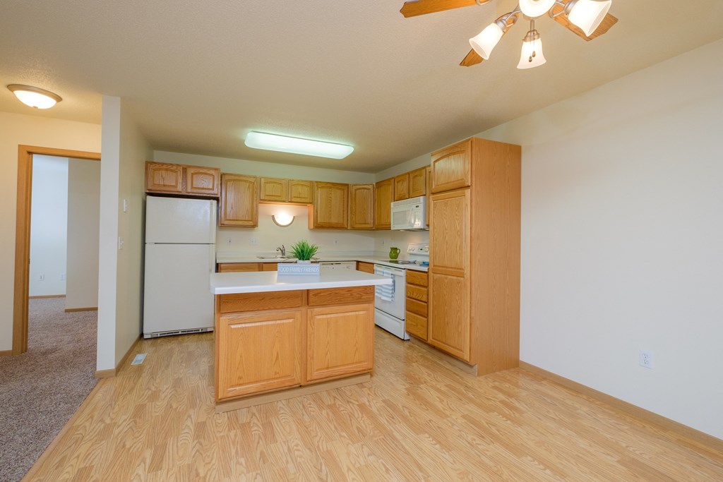 An empty kitchen with wooden cabinets and a white refrigerator