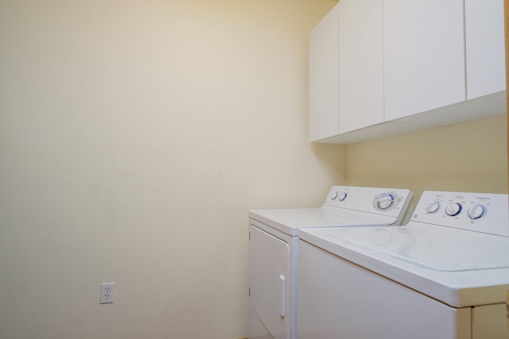 A washer and dryer in a laundry room with white cabinets