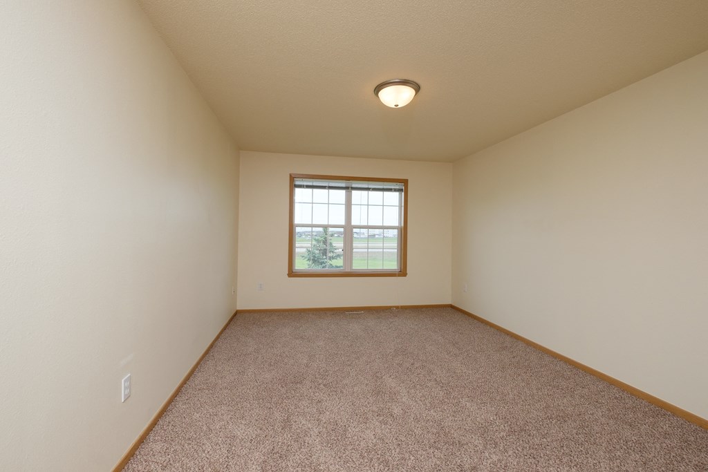 A bedroom with carpeted floors and a window.