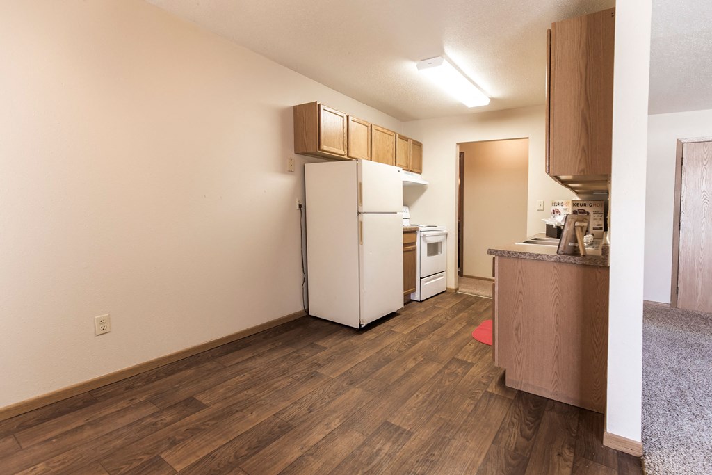 Grand Forks, ND Cherry Creek Apartments. A bedroom in unit 223 that has a window, white walls, and carpeted floors