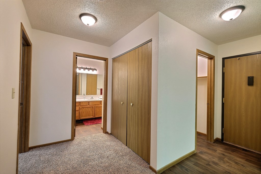 the view of a bedroom and bathroom from the hallway of a home with wooden doors. Fargo, ND Chestnut Ridge Apartments