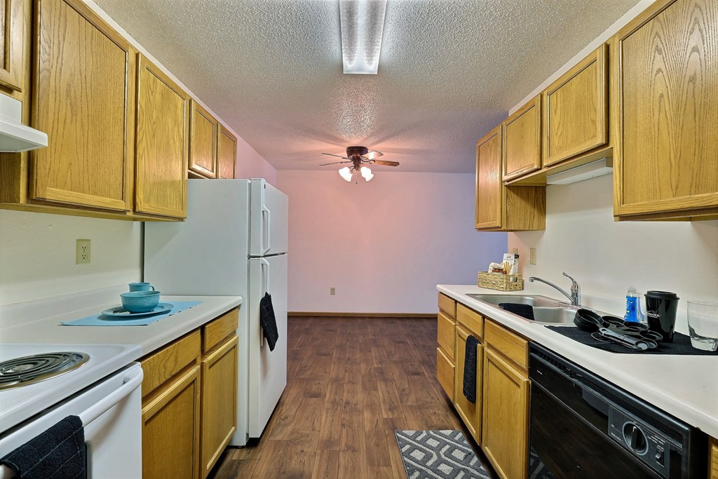 a kitchen with white appliances and wood cabinets. Fargo, ND Chestnut Ridge Apartment