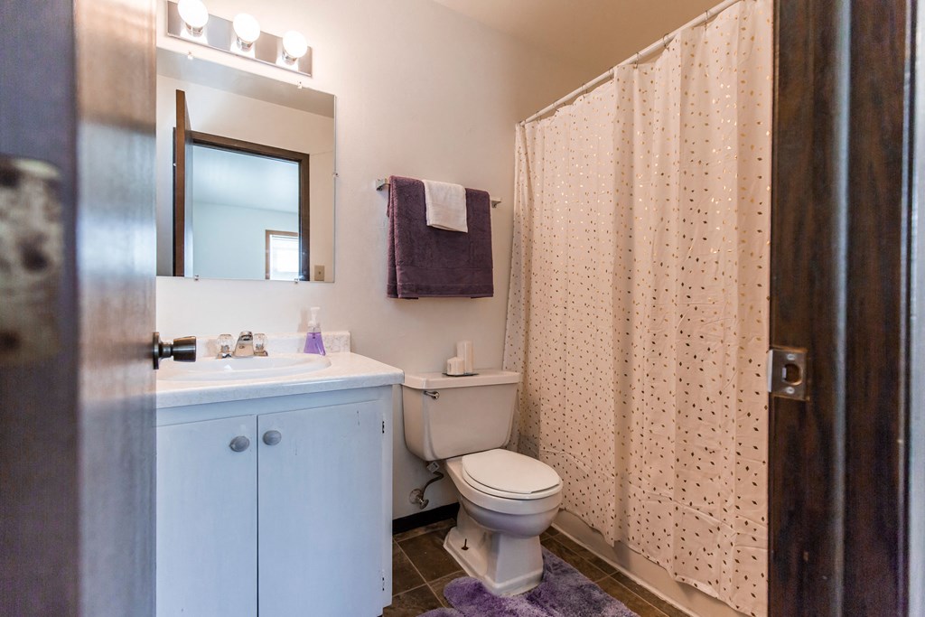 Grand Forks, ND Claremont Apartments. A bathroom with white cabinets a sink, toilet, and bathtub.