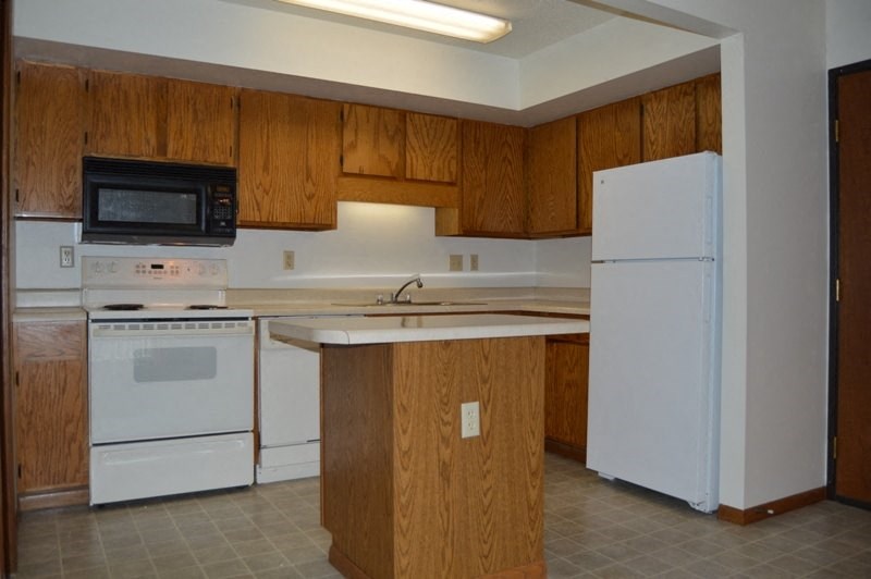 a kitchen with white appliances and wooden cabinets