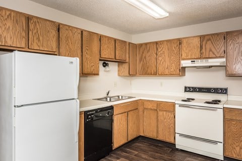 Grand Forks, ND Columbia West Apartments. a kitchen with white appliances and wooden cabinets