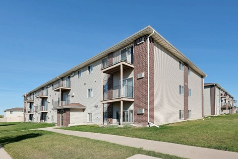 an apartment building with a sidewalk in front of it. Fargo, ND Country Edge Apartments