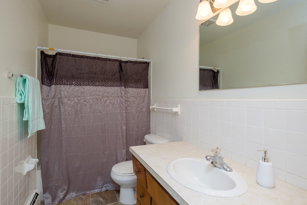 a bathroom with a shower and a sink and a toilet. Fargo, ND Country Club Apartments.