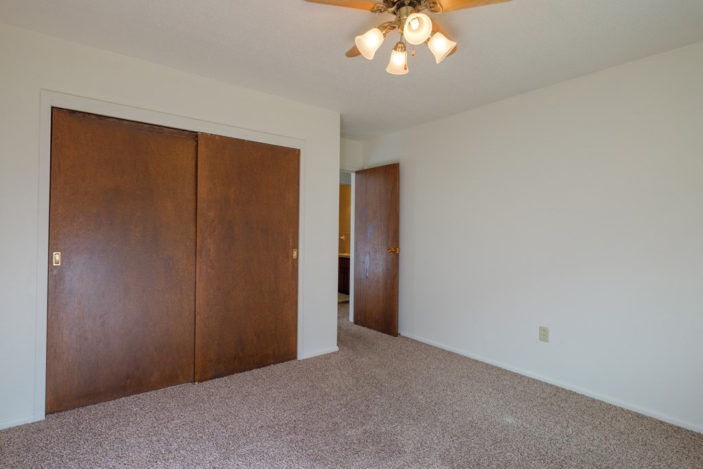 a bedroom with a closet and a ceiling fan. Fargo, ND Country Club Apartments.