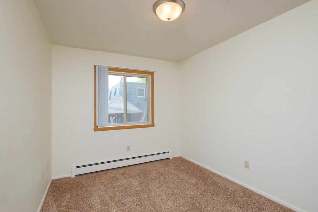 an empty living room with carpet and a window. Fargo, ND Country Club Apartments.