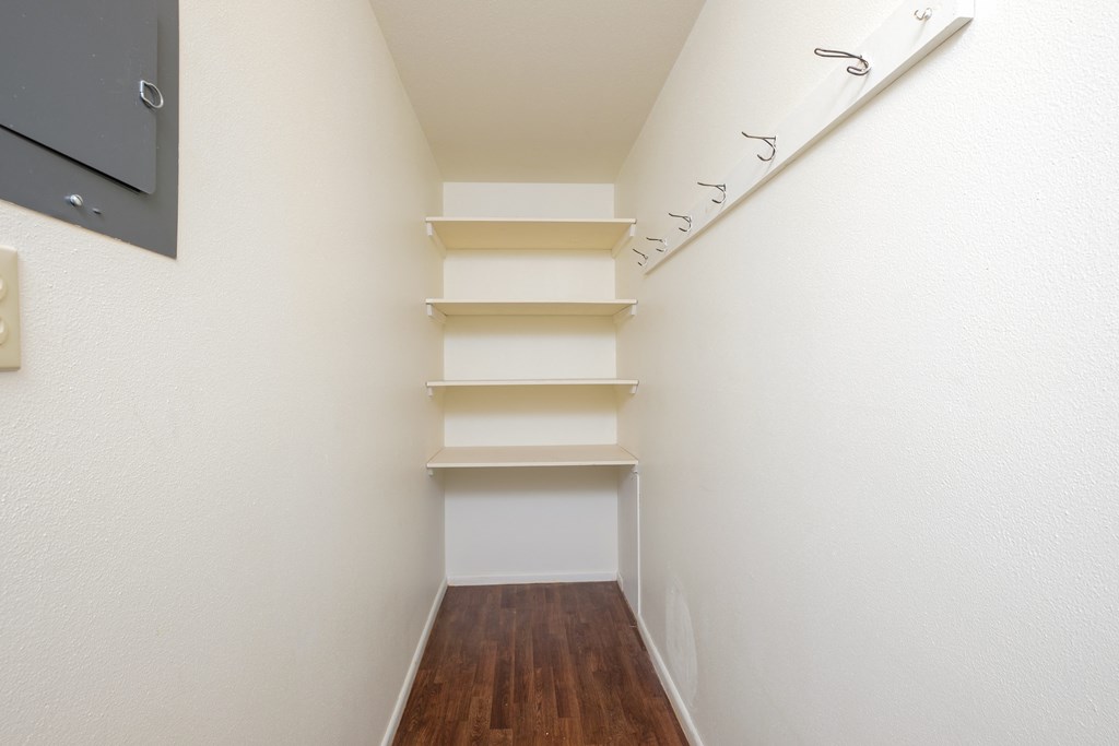 a corridor with white walls and shelves and a wood floor. Fargo, ND Country Club Apartments.