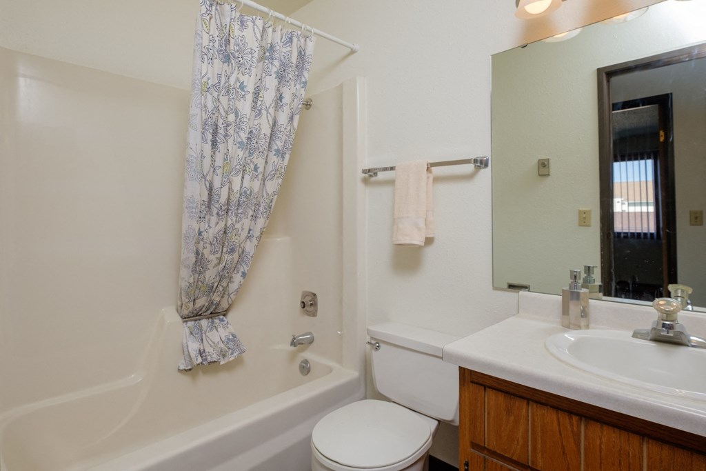 a bathroom with a sink toilet and tub and a mirror. Fargo, ND Countryside Apartments