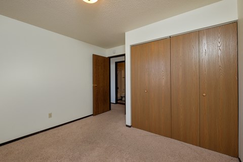 a bedroom with a closet and a door to a hallway. Fargo, ND Countryside Apartments.