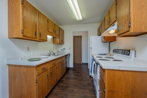 a kitchen with white appliances and wooden cabinets and a white stove. Fargo, ND Countryside Apartments