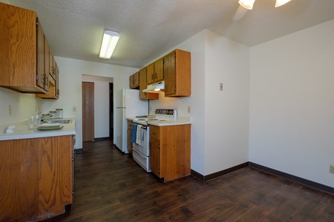 an empty kitchen with wooden cabinets and a stove and a refrigerator. Fargo, ND Countryside Apartments