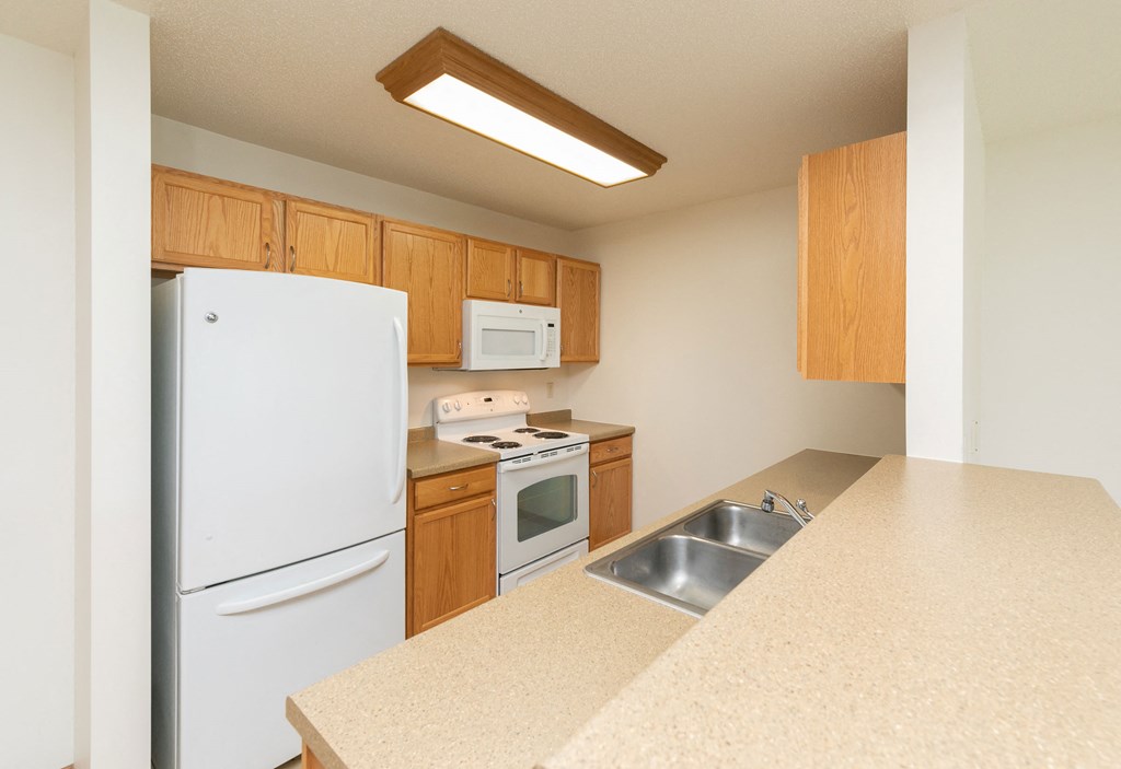 Fargo, ND Sunrise North | Kitchen a kitchen with white appliances and wooden cabinets. Fargo, ND Sunrise North