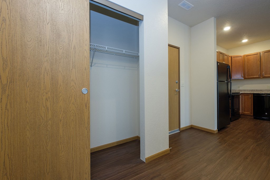 a door opens into a kitchen with a black refrigerator. Fargo, ND North Sky Apartments