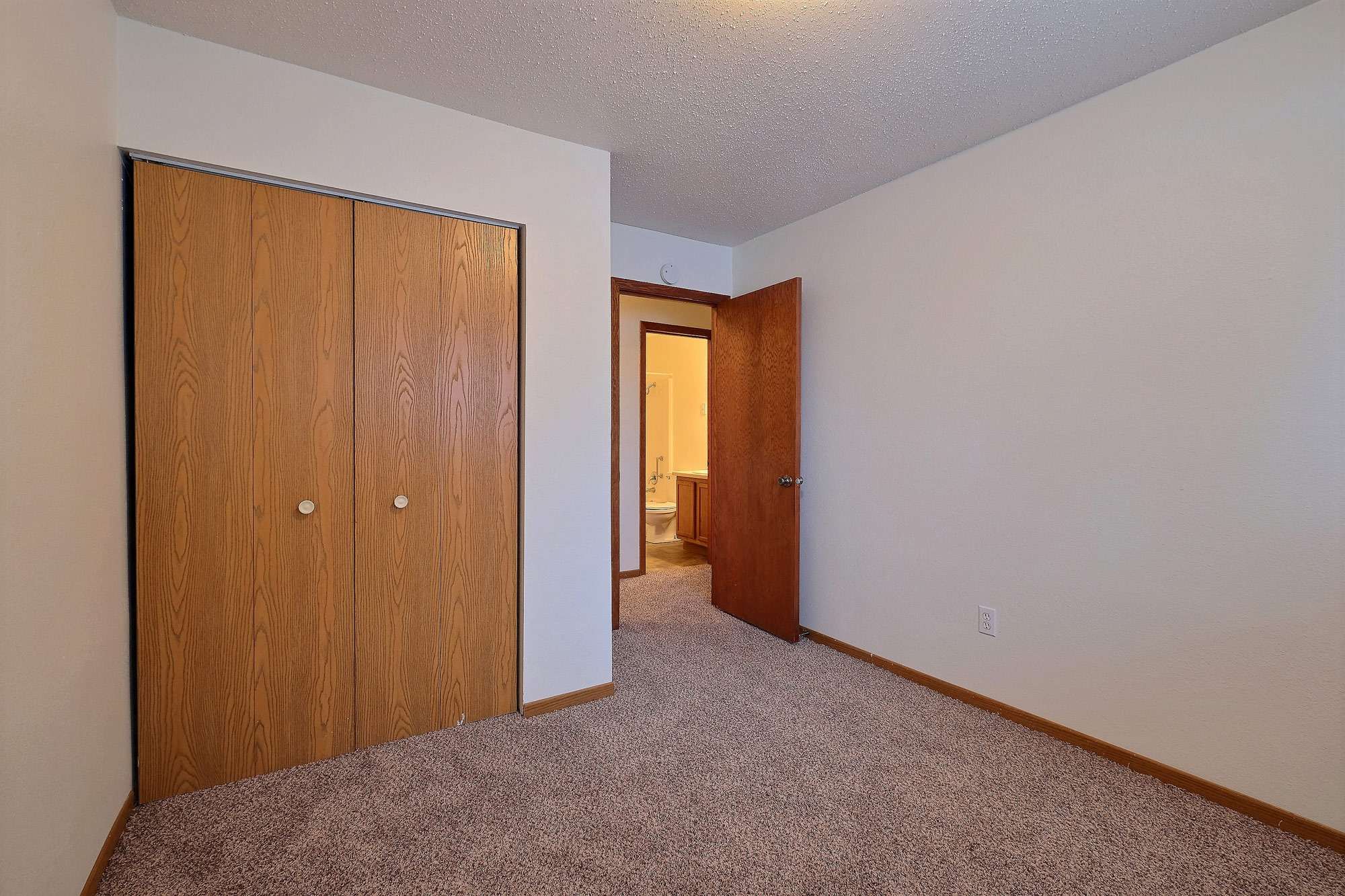 a bedroom with a closet and carpeted floors. Fargo, ND Dakota Manor Apartments