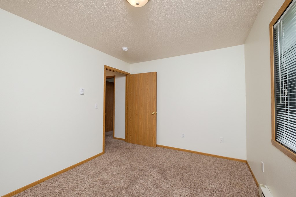 a bedroom with carpet and a door to a bedroom. Fargo, ND Danbury Apartments