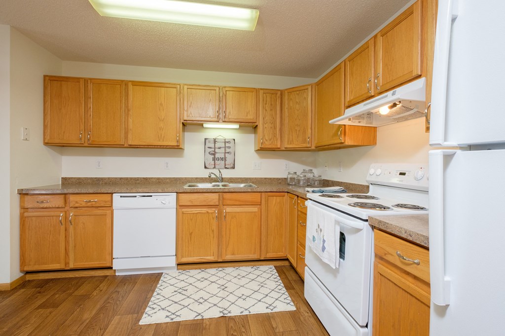 Fargo, ND Danbury Apartments | Kitchen a kitchen with white appliances and wooden cabinets. Fargo, ND Danbury Apartments