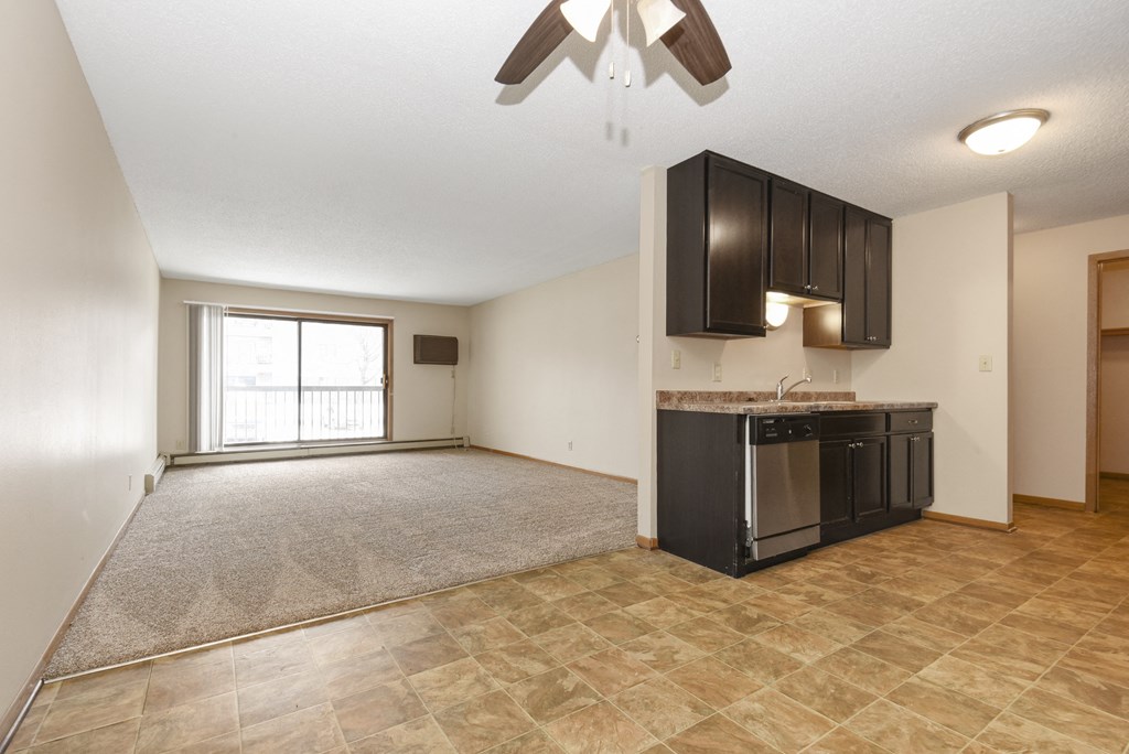 Anoka, MN Dellwood Estates Apartments. a kitchen and living room with a large window and a ceiling fan