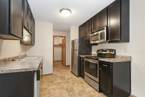 Anoka, MN Dellwood Estates Apartments. a kitchen with black cabinets and stainless steel appliances