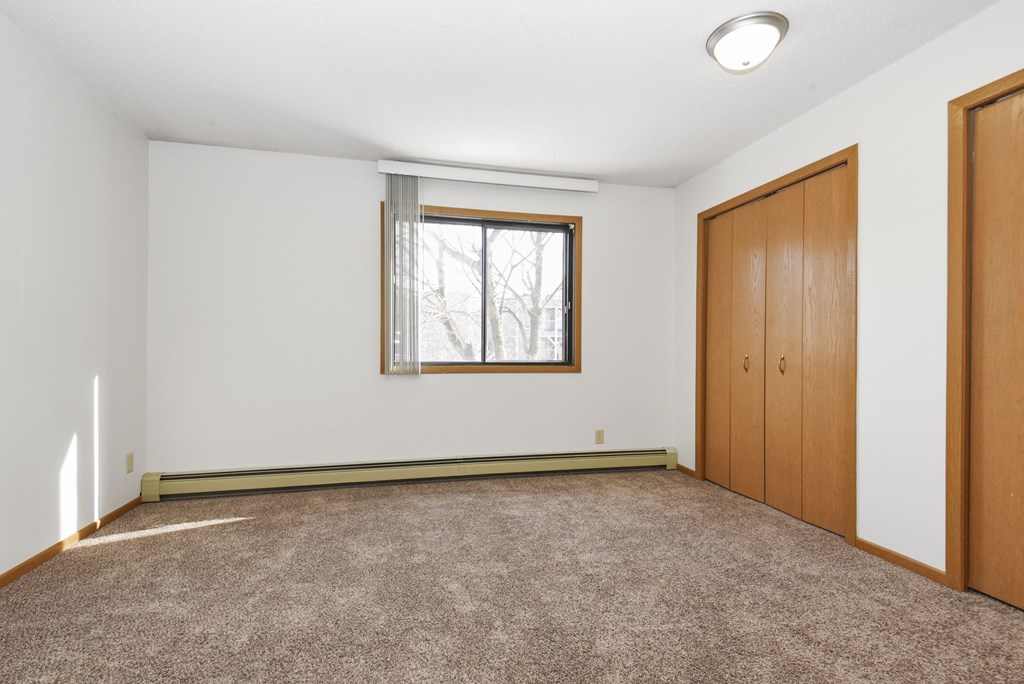 an empty room with carpet and a window and a door. Anoka, MN Dellwood Estates