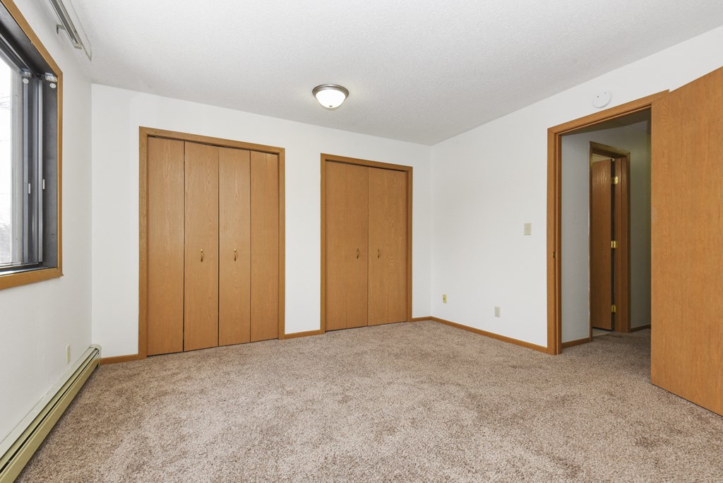 an empty living room with three doors and carpeting. Anoka, MN Dellwood Estates