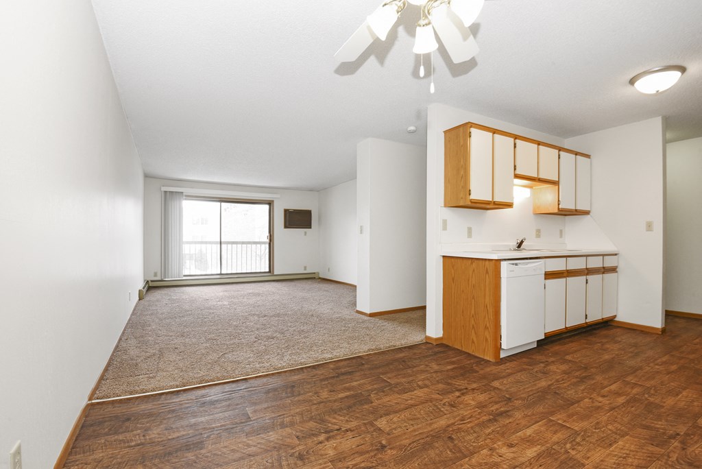 an empty living room and kitchen with wood flooring and a window .Anoka, MN Dellwood Estates
