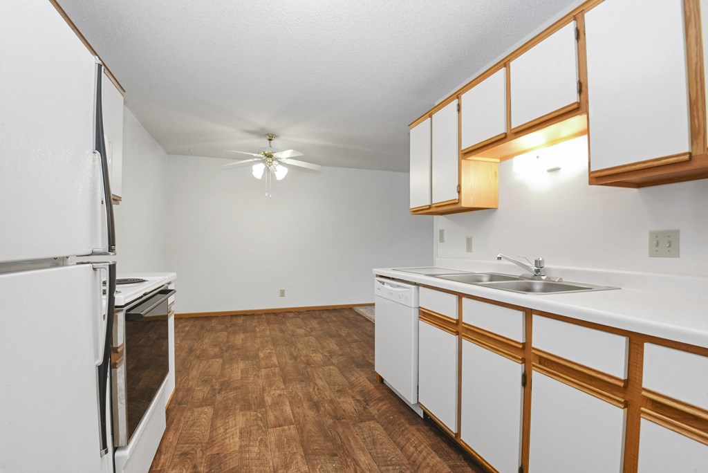 a kitchen with white cabinets and stainless steel appliances and a wood floor. Anoka, MN Dellwood Estates