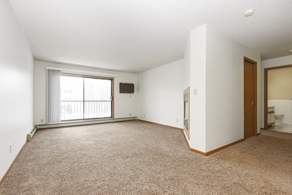 an empty living room with a window and a door to a bathroom. Anoka, MN Dellwood Estates