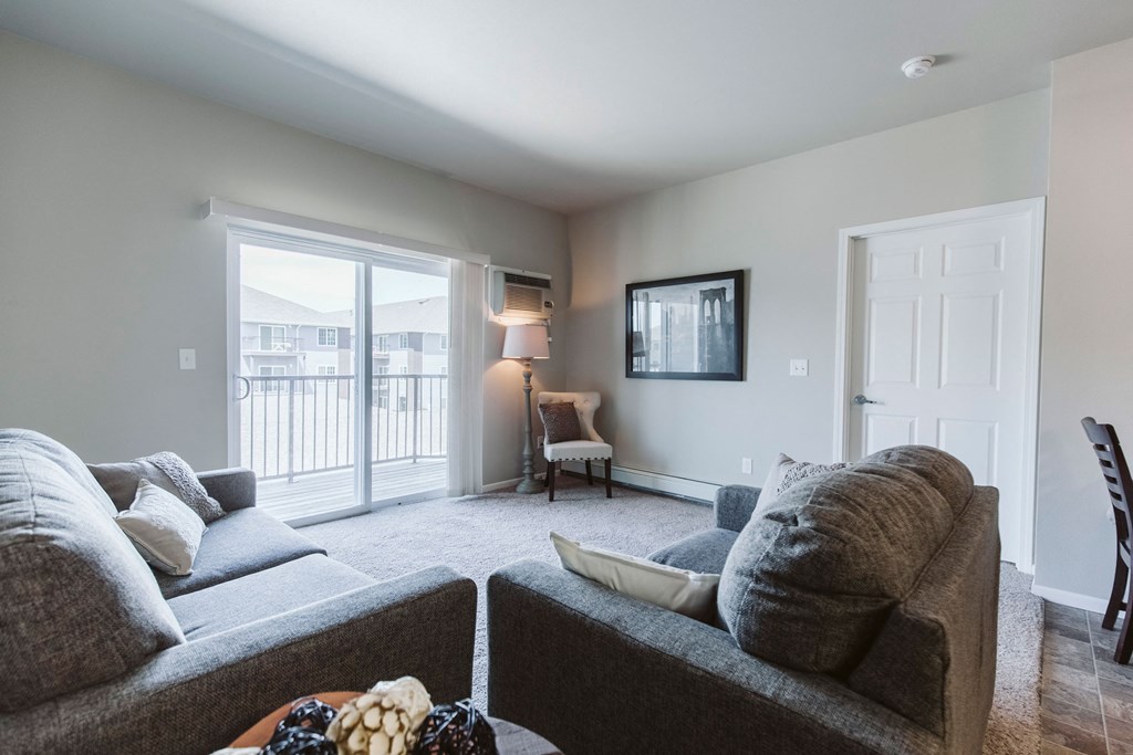 Bismarck, ND Diamond Bend Apartments. a living room with a couch and chair in front of a sliding glass door