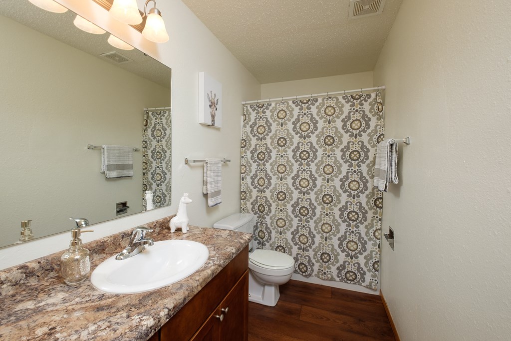 a bathroom with a sink and a toilet and a shower. Fargo, ND Dynasty Apartments