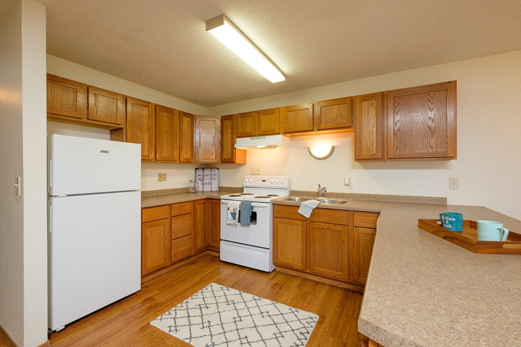 a kitchen with white appliances and wooden cabinets. Fargo, ND Dynasty Apartments