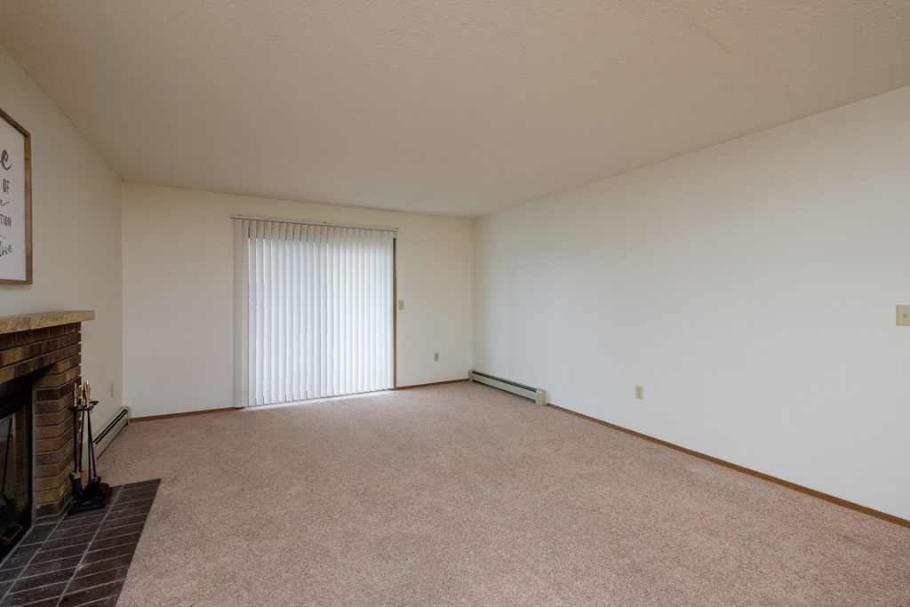 Fargo, ND Dynasty Apartments | Living a living room with a fireplace and a sliding glass door. Fargo, ND Dynasty Apartments